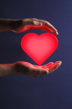 Man holding a glowing red heart in his hands