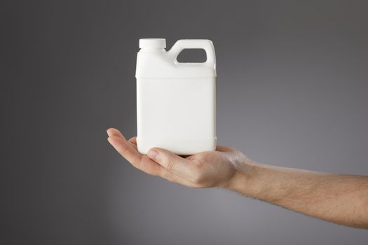 A Hand holding a small blank white plastic container.