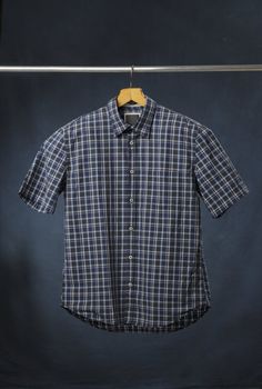 A new men's blue plaid cotton shirt hanging on a hanger.