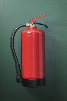 Red fire extinguisher mounted on a green wall