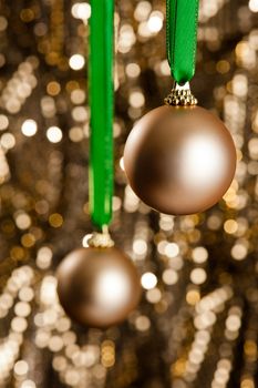 Two gold Christmas baubles in front of a gold glitter background for decoration purpose or Christmas use