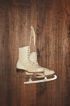 A Pair of old women's old skates hanging on a wooden wall. Photographed with a ring flash.