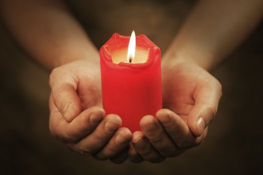 Man holding a red candle in his hands. Very short depth-of-field.