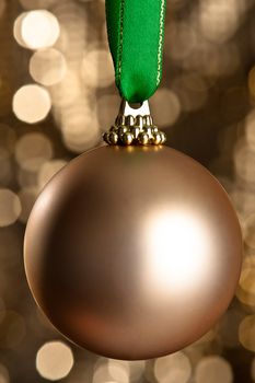 Single gold Christmas bauble in front of a gold glitter background for Christmas issues or other decoration issues