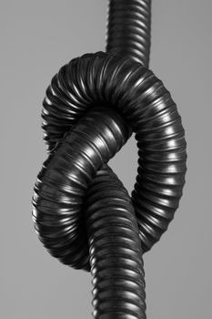 Knot on a flexible plastic hose. Black & white image.