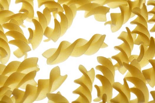 Uncooked pasta fusilli on white background