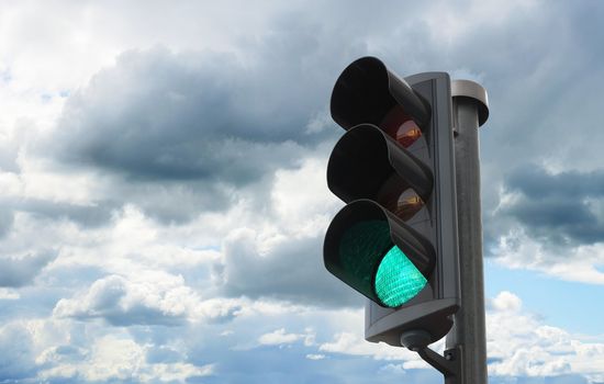 Traffic light with green light lit against sky