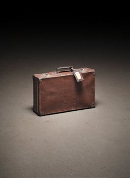 Old brown suitcase abandoned on dirty concrete floor