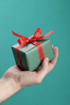 Man holding a small gift box with ribbon in his hand.