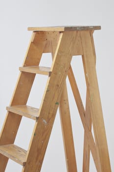 Old wooden stepladder against gray background