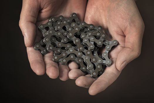 Man holding a new bicycle chain in his hands.