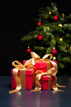 Three presents with gold ribbon in an elegant Christmas setting