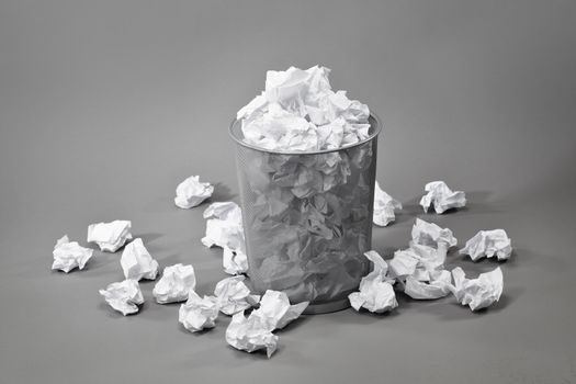 A trashcan filled with crumpled white papers