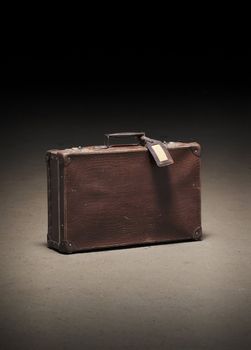 Old worn brown suitcase on dirty concrete floor