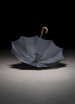 Old black umbrella upside down on dirty concrete floor
