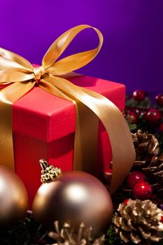Red present box in an elegant Christmas decoration, in front of a purple background