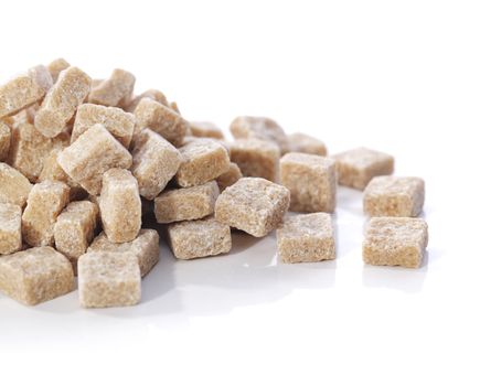 Natural brown sugar cubes on white reflecting background