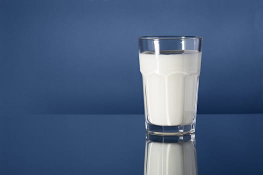 A Glass of milk on reflective blue background