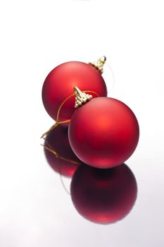 Red Christmas baubles on a silver reflective surface