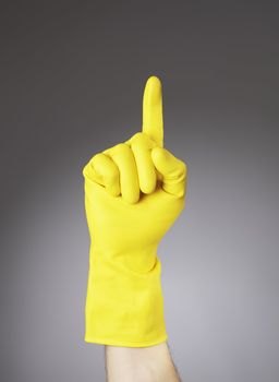 A Hand with yellow protective glove pointing with index finger