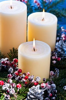 Three candles in an advent flower arrangement for advent and Christmas