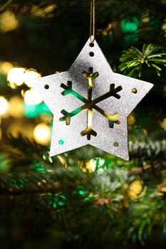 Decorative Silver Star ornament in a Christmas tree infront of a glitter background