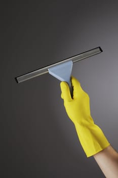 Hand with a yellow protective glove holding a rubber blade squeegee