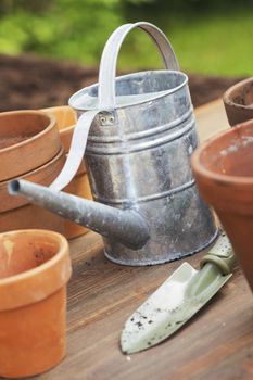 Gardening equipment: clay flower pots, metallic watering can and a small shoverl.