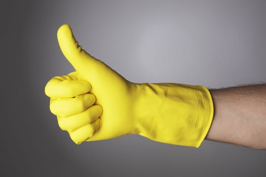 A Hand with yellow protective glove doing a thumb up sign