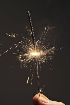 Fingers holding a burning sparkler