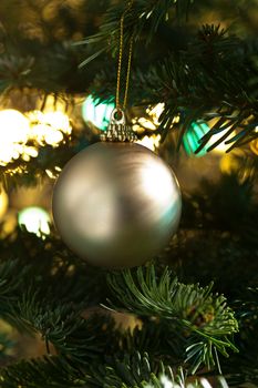 Decorative gold bauble in a Christmas tree in front of a glitter background