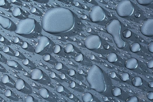 Water beads on a metallic blue car. The image may appear noisy, but it's just the metallic paint.