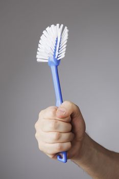 A Hand holding a blue dish brush