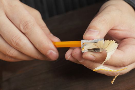 Hands sharpening a pencil with a pencil sharpener