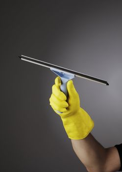 Hand with yellow protective rubber glove holding a squeegee