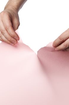 Man tearing pink paper with his hands.