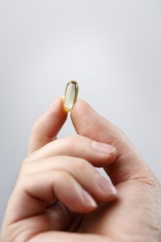 Fingers holding an Omega 3 fish oil capsule