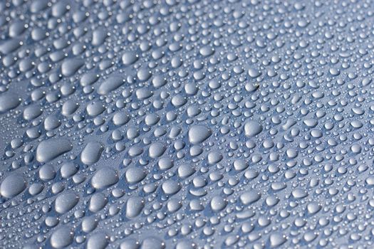 Water droplets on a car. Short depth-of-field, some sharpness in the middle and bottom left.