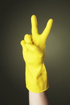 A Hand with yellow protective rubber glove doing a "V" sign
