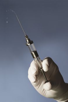 Hand squeezing an old glass syringe with a sharp needle