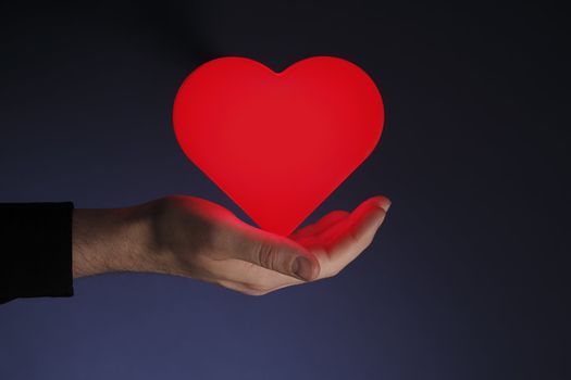 Man holding a glowing red heart in his hand