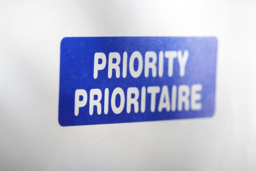 A blue "Priority" sticker on an envelope. Short depth-of-field