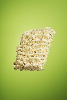 A block of dry instant ramen noodles on green background