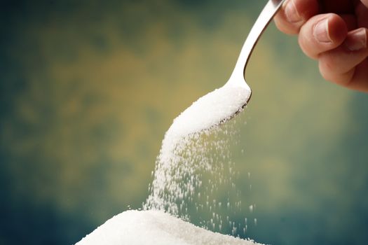 Adding sugar with a spoon.