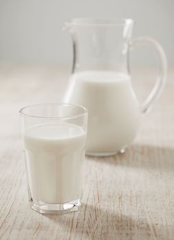 A Glass of milk. Milk jug in the background.