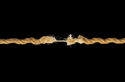 A natural fibre rope breaking against black background