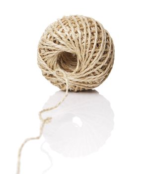 A Roll of natural fiber string on reflective background.