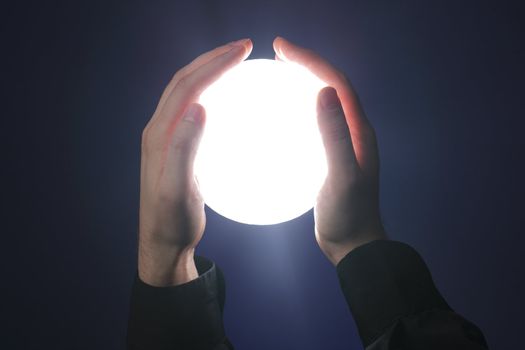 Hands holding a glowing sphere shaped object