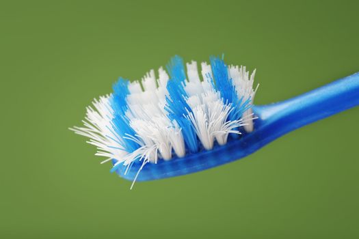 Old and worn toothbrush on green background