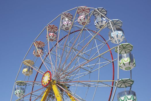 A Ferris wheel without passengers against clear blue sky.